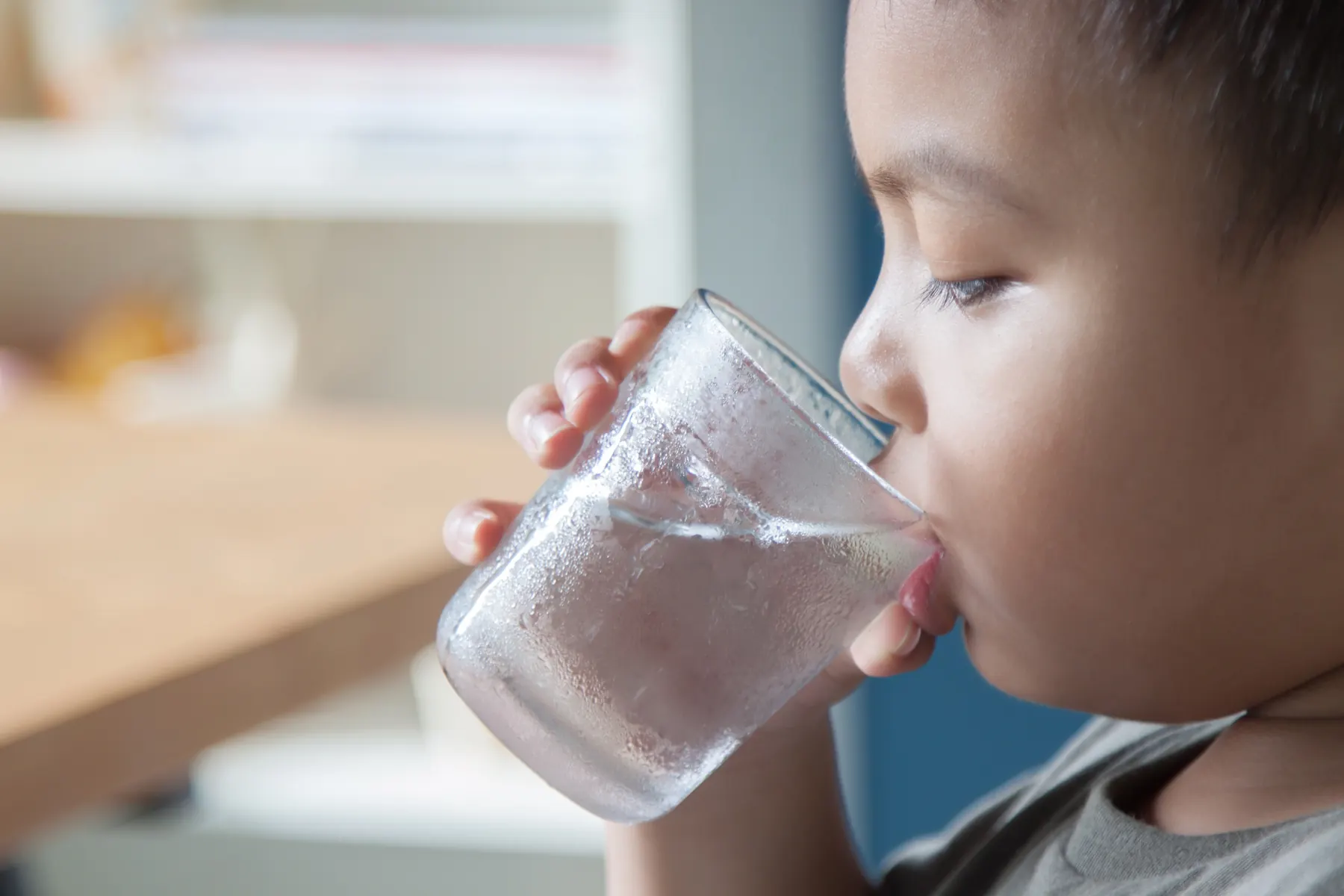 Child drinking from a frosted glass of water